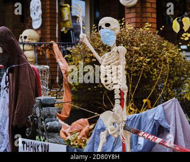 Ottawa, Kanada. Oktober 2020. Covid 19 Themen Halloween Dekorationen an der Vorderseite eines Hauses in der Glebe. Skelett trägt eine Maske, und in kanadischer Mode bitten die Menschen, einen Hockeyschläger auseinander zu halten für soziale Distanzierung. Mit Oktober 31 nähern Ottawa Public Health sowie die Regierung von Ontario haben die Menschen gebeten, ihre Trick oder Behandlung Pläne in diesem Jahr stornieren, und stattdessen organisieren haushaltsspezifische Aktivitäten. Kredit: Meanderingemu/Alamy Live Nachrichten Stockfoto