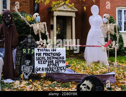 Ottawa, Kanada. Oktober 2020. Covid 19 Themen Halloween Dekorationen an der Vorderseite eines Hauses in der Glebe. Skelett trägt eine Maske, und in kanadischer Mode bitten die Menschen, einen Hockeyschläger auseinander zu halten für soziale Distanzierung. Mit Oktober 31 nähern Ottawa Public Health sowie die Regierung von Ontario haben die Menschen gebeten, ihre Trick oder Behandlung Pläne in diesem Jahr stornieren, und stattdessen organisieren haushaltsspezifische Aktivitäten. Kredit: Meanderingemu/Alamy Live Nachrichten Stockfoto