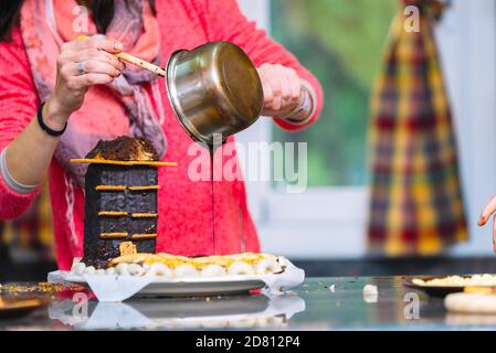 Nahaufnahme einer Frau, die Schokolade auf Kuchen gießt Stockfoto