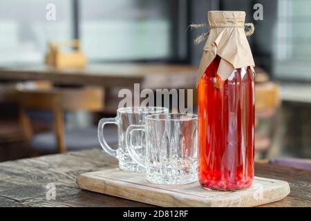 Kombucha Tee mit Beeren in Glasflasche neben Glas Tassen. Gesundes fermentiertes Getränk Stockfoto