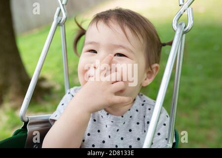 Lächelndes Kleinkind Mädchen mit Pigtails schwingt glücklich im Freien Stockfoto