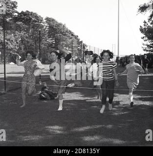 1960s, historische, Mädchen, die am Wettlauf Rennen draußen auf einem Sommerfest, mit mehreren in der Nähe der Ziellinie und ein Paar sind gestolpert und sind auf dem Gras, Fife, Schottland. Stockfoto