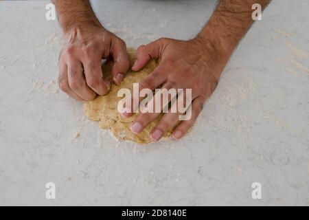 Die Hände des Mannes kneten den Teig aus nächster Nähe Stockfoto