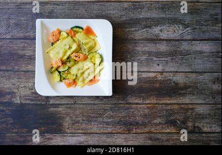 Deutsche Hausmannskost: Maultaschen (gefüllte Pasta - auch „Schwäbische Ravioli“ genannt) mit Lachs und Zucchini. Stockfoto