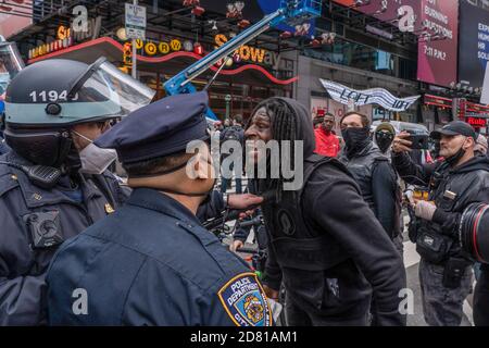 Ein Anti-Trump-Protestler konfrontiert NYPD Polizeibeamte während des Protests.Pro-Präsident Trump Anhänger marschieren entlang der 5. Avenue mit Karawane von Autos und riesigen Trump blau, weiß, schwarz Flagge. Sie marschieren vom Trump Tower auf der 5th Avenue zur 42nd Street und von dort zum Times Square, wo sie sich mit Gegenprotestierenden trafen. Die Anti-Trump-Demonstranten schleuderten Beleidigungen und Gegenstände wie mit Farbe gefüllte Flaschen und Eier. Es gab viele Handgemenge zwischen diesen beiden Gruppen und die Polizei machte mehr als ein Dutzend Verhaftungen. Stockfoto