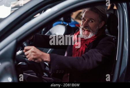 Happy stylish Senior Mann mit grauen Haaren und Schnurrbart ist Im modernen Auto Stockfoto