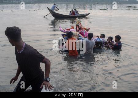 Hinduistische Anhänger tauchen das Idol der Hindu-Göttin Durga auf dem Buriganga Fluss ein am letzten Tag des Durga Puja Festivals wird das viertägige Durga Festival in ganz Bangladesch gefeiert und gipfelt im Eintauchen der Idole der Hindu-Göttin Durga, um Macht und den Triumph zu symbolisieren Gut über Böse in der hinduistischen Mythologie. Stockfoto