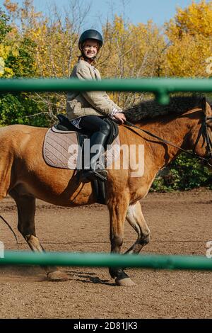 Happy Little Ingwer Mädchen Reiten auf einem kleinen braunen Pferd. Zügel halten. Stockfoto