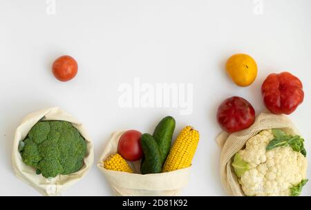 Gemüse in Öko-Beutel auf weißer Oberfläche mit einem Kopierplatz. Pfeffer, Tomaten, Mais, Gurke, Brokkoli, Blumenkohl in wiederverwendbaren Einkaufen umweltfreundlich Stockfoto
