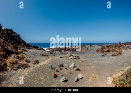 Strand mit vulkanischer Landschaft, Steinen und Felsen mit Meer auf Lanzarote, Spanien. Stockfoto
