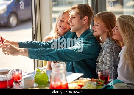Überglücklich kaukasische Menschen posieren für Foto im Café zusammen, Selfie auf dem Smartphone, posieren für Foto im Café zusammen, Aufnahme Video für soziale Netzwerk, Spaß mit Freunden. Seitenansicht Stockfoto