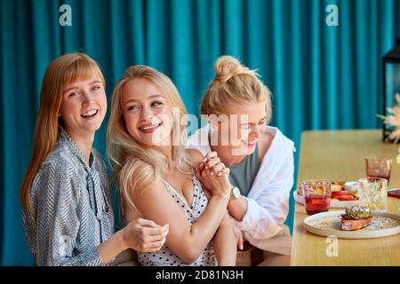 Freundinnen lachen, Spaß haben, während im Restaurant sitzen. Mittagspause der schönen blonden Frauen, Freizeit, Spaß, Freundschaft Konzept Stockfoto