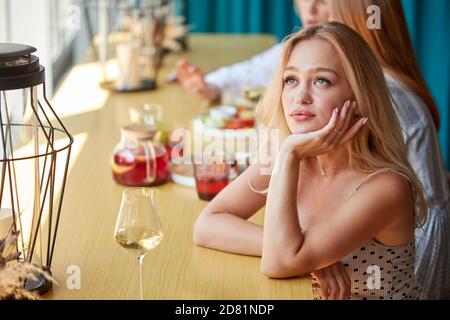 Gelangweilte kaukasische Frau sitzt allein im Restaurant, warten auf jemanden auf Datum, Treffen. Oder warten auf Essen, das sie bestellt Stockfoto