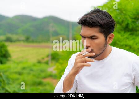 Junger Mann rauchen Zigarette im Freien und Natur Hintergrund. Stockfoto
