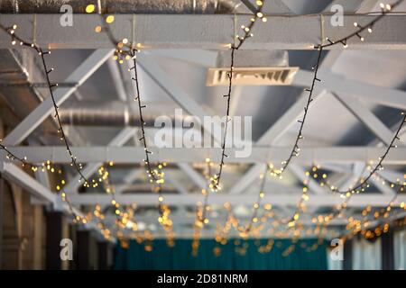 Kleine Girlanden an der Decke im Restaurant oder Café, Interieur und Design-Konzept. Architektonische Beleuchtung des Raumes im Retro-Stil, keine Menschen Stockfoto