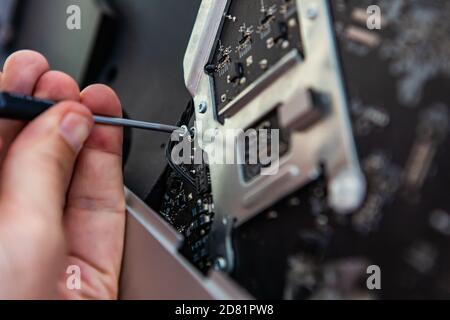 Selektiver Fokus des Computertechnikers Hände halten Schraubendreher Werkzeug zu Öffnen Sie die Schrauben vom Desktop aus, während Sie das Problem analysieren und lösen Stockfoto