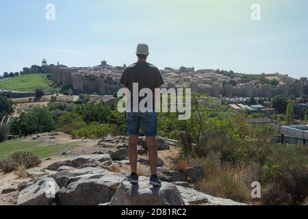 Junger Mann in kurzen Hosen, der die Wände von Avila beobachtet In Spanien an einem sonnigen Tag Stockfoto