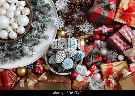 Draufsicht weihnachtsdekorationen Herzstück mit Girlande und Kugeln in der Nähe eines Korbes mit bunten Kieferkegel, isoliert auf Geschenk verpackt Pakete Stockfoto