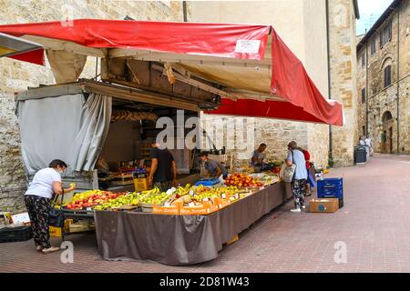 Die Menschen einkaufen an einem Obst-und Gemüsemarkt in der Altstadt von San Gimignano, UNESCO-Weltkulturerbe, Siena, Toskana, Italien Stockfoto