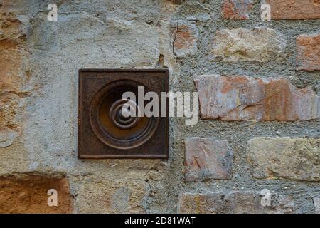 Nahaufnahme einer alten rostigen Türklingel auf einem Backstein Wand Hintergrund, San Gimignano, Siena Toskana, Italien Stockfoto