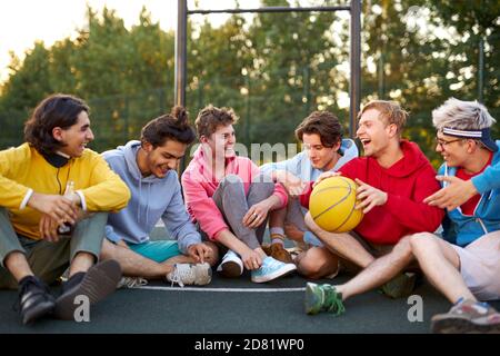 Junge Basketballspieler machen nach dem Spiel eine Pause, haben Spaß und reden. Im Spielplatz Stockfoto