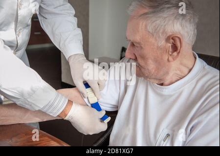 Hände eines Arztes oder eines Arztes sterile Handschuhe, die einen Abbindung auf die Hand eines alten Mannes auftragen. Vorbereitung für die Blutentnahme oder Stockfoto