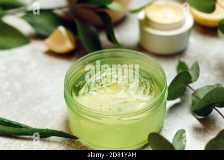 Eine Dose Aloe Gel neben einem Aloe Zweig und Eukalyptusblättern. Das Konzept der Hautpflege, Liebe für Ihren Körper, natürliche Inhaltsstoffe. Stockfoto