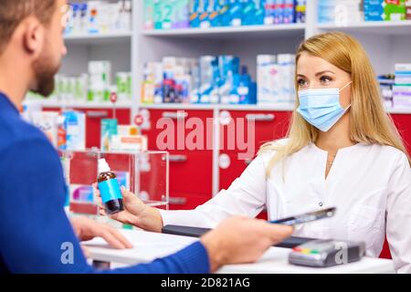 Junge weibliche Apotheke mit Droge und männliche Kunden in der Apotheke, Hilfe, Beratung. Medizin, Pharmazie, Gesundheitswesen und Menschen Konzept Stockfoto