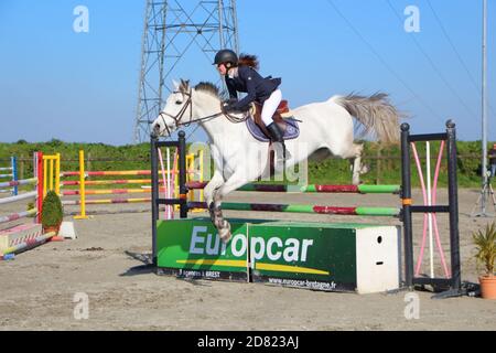 PLABENNEC, FRANKREICH - MÄRZ 25 : Frau und graues Pferd springen ein Hindernis während einer Reitveranstaltung, 25. März 2017 Stockfoto