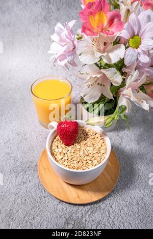 Gesundes Frühstück mit einer Schale Hafer, Erdbeer und Orangensaft auf Betongrund. Leerzeichen für Text. Für Text platzieren. Geschichten Bio-Lebensmittel Vorlage Stockfoto