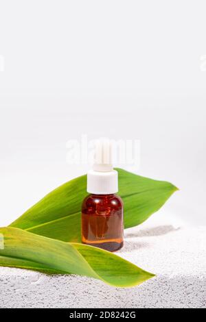 Natürliche Kosmetologie Hintergrund. Eine Glasflasche mit Pipette auf Öko-Materialien wie Zement, Blatt, Querschnitt des Baumes Stockfoto