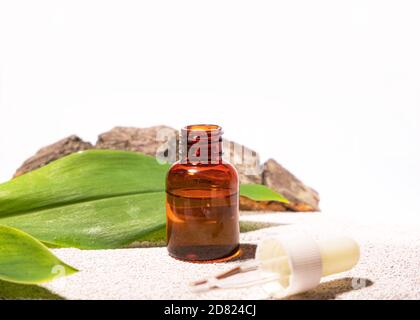 Natürliche Kosmetologie Hintergrund. Eine Glasflasche mit Pipette auf Öko-Materialien wie Zement, Blatt, Querschnitt des Baumes Stockfoto