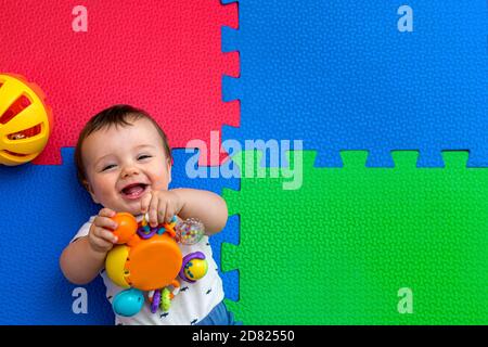 Lustige Baby spielen auf bunten eva Gummiboden. Kleinkind mit Spaß in seinem Haus. Draufsicht. Stockfoto