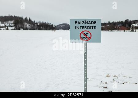 Schild der Baignade Interdite in französisch geschrieben bedeutet, dass kein Schwimmen Mit Illustrator auf Eisschicht ohne Menschen herum Stockfoto
