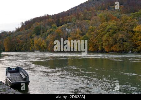 Ein Boot am Ufer der Aare in Aarburg in der Schweiz mit Herbstlandschaft im Hintergrund. Es gibt bunte Herbstblätter. Stockfoto