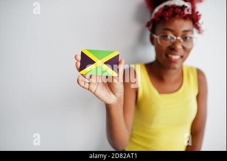 afroamerikanische Frau mit afro Haar, tragen gelbe Singlet und Brillen, halten Jamaika Flagge isoliert auf weißem Hintergrund. Stockfoto