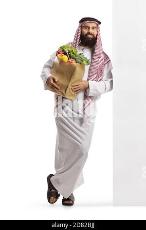 Arabischer Mann mit einer Lebensmitteltasche stehend und anlehnend Eine Wand isoliert auf weißem Hintergrund Stockfoto