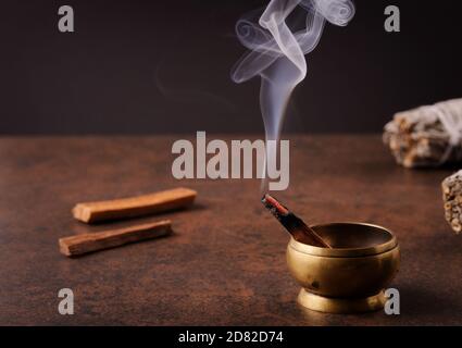 Aromatischer Stock Pala Santo Brennen und Rauchen auf dunkelbraunem Hintergrund. Das Konzept der Reinigung von Körper und Seele, Heilung, Meditation. Stockfoto