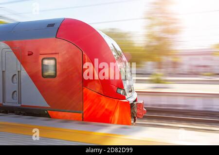 Der Pendlerzug fährt mit hoher Geschwindigkeit durch den Passagierbahnhof, den Kopfwagen und die Seitenansicht des Fahrerhauses Stockfoto