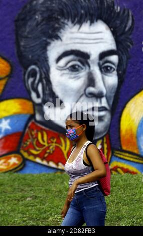 Valencia, Carabobo, Venezuela. Oktober 2020. Bildunterschrift: 26. Oktober 2020. Eine Frau, die eine Anti-Covid Gesichtsmaske trägt, geht vor einem Graffiti des Liberators Simon Bolivar. Simon Bolivar befreite 5 südamerikanische Nationen vom spanischen Joch, seiner Heimat Venezuela, Kolumbien, Peru, Ecuador und Bolivien.Dies ist eine Hommage des Bürgermeisteramtes von Valencia, Carabobo, Venezuela - Foto: Juan Carlos Hernandez Kredit: Juan Carlos Hernandez/ZUMA Wire/Alamy Live News Stockfoto