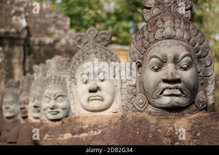 Nahaufnahme von Asuras (Dämonen) Statuen in einer Reihe am südlichen Eingangstor des Bayon Tempels in Siem Reap, Kambodscha Stockfoto