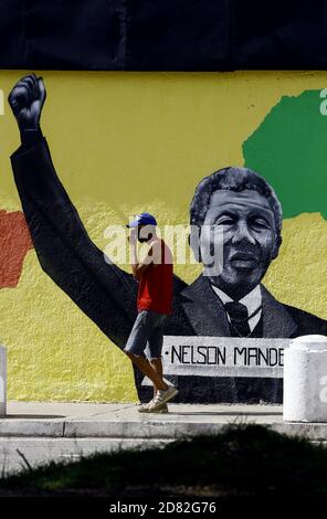 Valencia, Carabobo, Venezuela. Oktober 2020. Bildunterschrift: 26. Oktober 2020. Ein Mann, der eine Covid-Schutz Gesichtsmaske trägt, geht vor Graffiti des afrikanischen Führers Nelson Mandela. Nelson Mandela war Rechtsanwalt und südafrikanischer politischer Aktivist des 20. Und 21. Jahrhunderts (er wurde am 18. Juli 1918 geboren und starb am 5. Dezember 2013 im Alter von 95 Jahren) und widmete sich dem friedlichen Kampf gegen die Rassentrennung in Südafrika. Dies ist eine Hommage des Bürgermeisters von Valencia, an die herausragenden Nachkommen des Afros. In Valencia, Carabobo, Venezuela - Foto: Juan Carlos Hernandez (Bild Des Kredits: Stockfoto