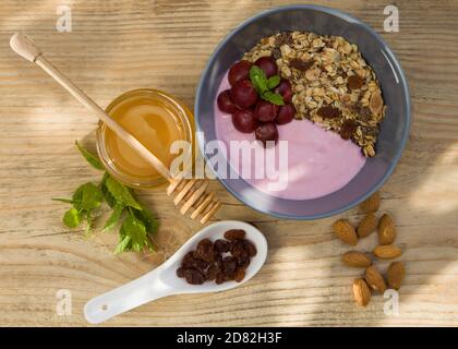 Gesundes Frühstück - Joghurt, Haferflocken, Haselnüsse, Honig. Konzept - diätetische und fit Catering. Essen auf einem Holztisch. Stockfoto