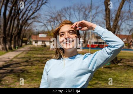 Junge blonde Frau im Park lächelt mit Zahnspangen Stockfoto