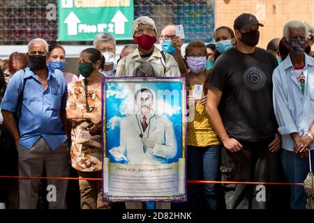 Caracas, Venezuela. Oktober 2020. Gläubige mit Gesichtsmasken stehen vor der Kirche "Nuestra Señora de la Candelaria", wo die Überreste des 1919 verstorbenen Arztes Jose Gregorio Hernandez ausgegraben werden. Die Exhumierung, die in Anwesenheit von Zeugen stattfand, wurde im Rahmen des Prozesses zur Seligsprechung der Venezolaner durchgeführt. Hernandez wird von vielen Gläubigen im südamerikanischen Land verehrt. Kredit: Pedro Rances Mattey/dpa/Alamy Live Nachrichten Stockfoto