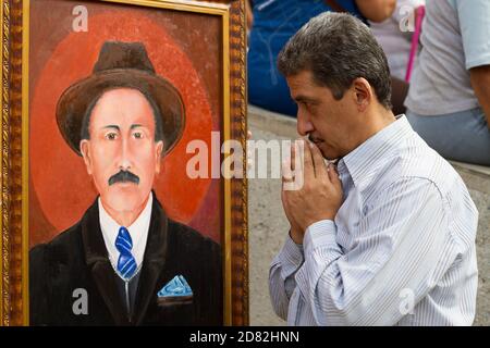 Caracas, Venezuela. Oktober 2020. Ein Gläubiger betet vor einem Bild des venezolanischen Arztes Jose Gregorio Hernandez, dessen Überreste in der Kirche "Nuestra Señora de la Candelaria" ausgegraben werden. Die Exhumierung erfolgte im Rahmen des Prozesses zur Seligsprechung des venezolanischen Arztes, der 1919 starb. Hernandez wird von Tausenden von Gläubigen im südamerikanischen Land verehrt. Kredit: Pedro Rances Mattey/dpa/Alamy Live Nachrichten Stockfoto