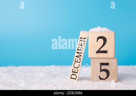 Weihnachtskarte Konzept. Nahaufnahme Foto von Blöcken Holzkalender zeigt 25 Dezember im Schnee isoliert auf blauem Hintergrund mit emp Stockfoto