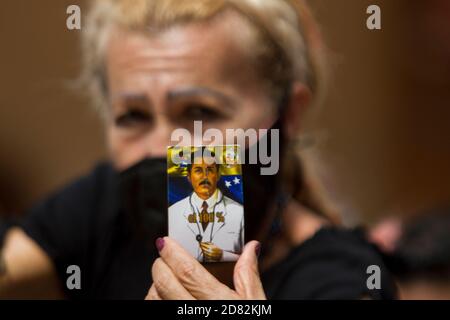 Caracas, Venezuela. Oktober 2020. Ein Gläubiger mit einem Mundschutz hält ein Bild des Venezolaners Jose Gregorio Hernandez hoch, während die sterblichen Überreste des 'Sints der Armen' in einer geschlossenen Zeremonie ausgegraben werden. Die Exhumierung, die in Anwesenheit von Zeugen stattfand, wurde im Rahmen des Prozesses zur Seligsprechung des 1919 verstorbenen Venezolaners durchgeführt. Hernandez wird von vielen Gläubigen im südamerikanischen Land verehrt. Kredit: Pedro Rances Mattey/dpa/Alamy Live Nachrichten Stockfoto