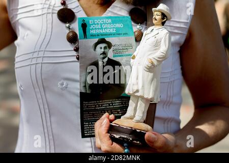 Caracas, Venezuela. Oktober 2020. Ein Gläubiger hält eine Figur des Venezolaners Jose Gregorio Hernandez, "Doktor der Armen", während dessen Überreste in einer geschlossenen Zeremonie ausgegraben werden. Die Exhumierung, die in Anwesenheit von Zeugen stattfand, wurde im Rahmen des Prozesses zur Seligsprechung des 1919 verstorbenen Venezolaners durchgeführt. Hernandez wird von vielen Gläubigen im südamerikanischen Land verehrt. Kredit: Pedro Rances Mattey/dpa/Alamy Live Nachrichten Stockfoto