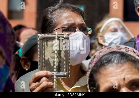 Caracas, Venezuela. Oktober 2020. Ein Gläubiger mit einem Mundschutz hält ein Bild des Venezolaners Jose Gregorio Hernandez und einen Rosenkranz hoch, während die sterblichen Überreste des 'Sints der Armen' in einer geschlossenen Zeremonie ausgegraben werden. Die Exhumierung, die in Anwesenheit von Zeugen stattfand, wurde im Rahmen des Prozesses zur Seligsprechung des 1919 verstorbenen Venezolaners durchgeführt. Hernandez wird von vielen Gläubigen im südamerikanischen Land verehrt. Kredit: Pedro Rances Mattey/dpa/Alamy Live Nachrichten Stockfoto